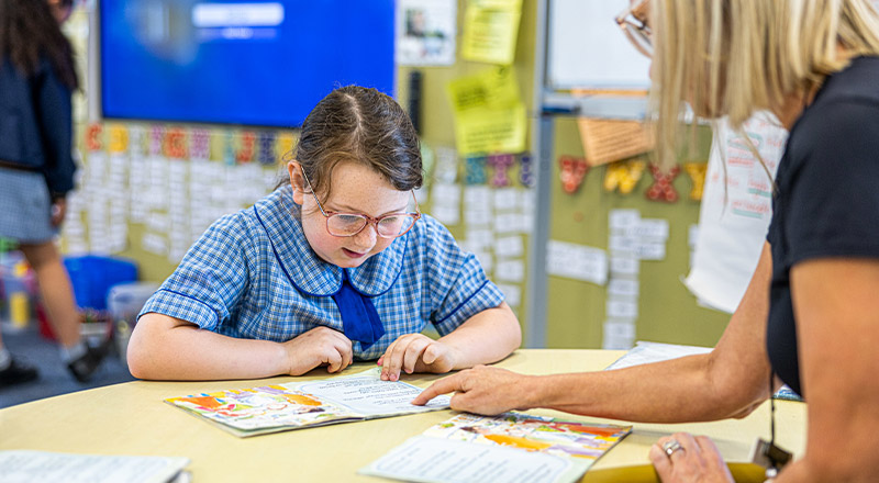 Student learning to read with a teacher at St Michael's Primary School Blacktown South
